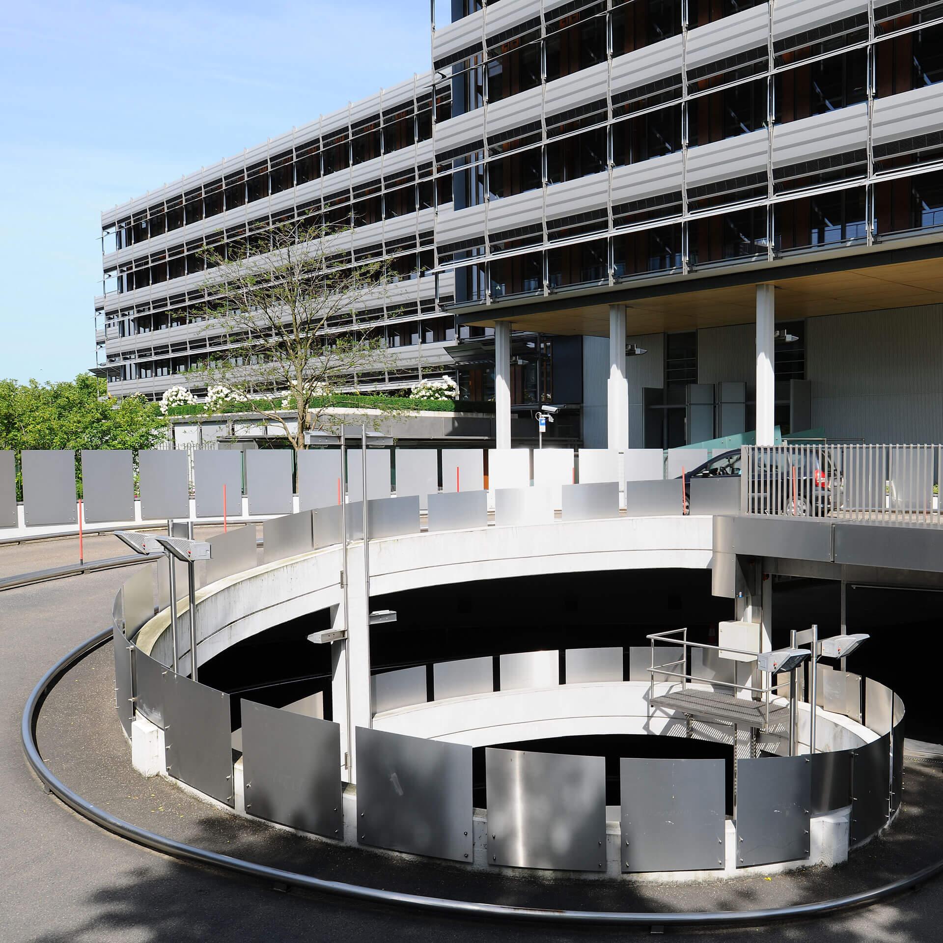 SOKA-BAU - spiralförmige Garageneinfahrt und zwei moderne Bürogebäude, Baum und Sträucher